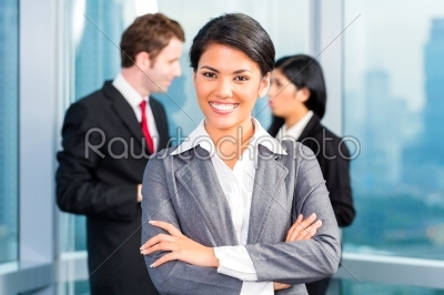 Asian business team in office, woman in front with skyline