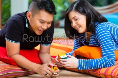 Asian couple at home playing with magic cube