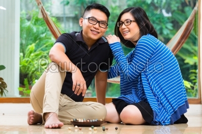 Asian couple at home playing with marbles