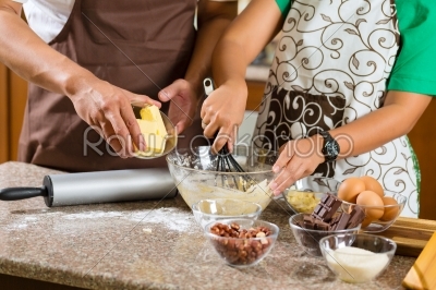 Asian couple baking cake in home kitchen