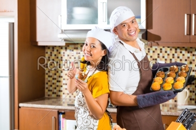Asian couple baking muffins in home kitchen