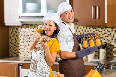 Asian couple baking muffins in home kitchen