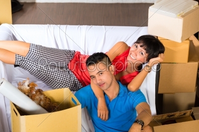 Asian couple having break while moving in