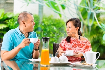Asian couple having coffee on home porch