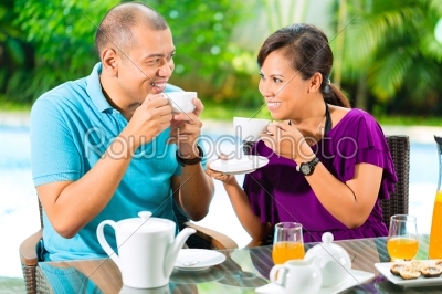 Asian couple having coffee on home porch