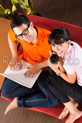 Asian couple on the couch with a laptop