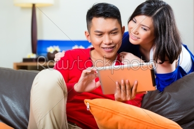 Asian couple on the couch with a tablet pc