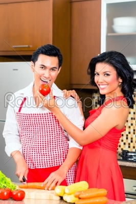 Asian couple preparing food in domestic kitchen