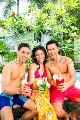 Asian friends drinking cocktails at pool