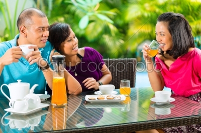 Asian friends having coffee on home porch