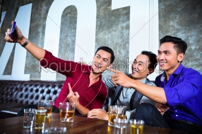 Asian friends taking pictures or selfies in fancy night club