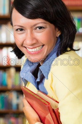 Asian girl at library holding a book