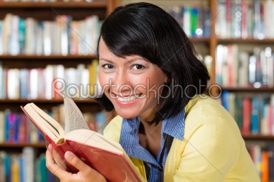 Asian girl in library reading a book