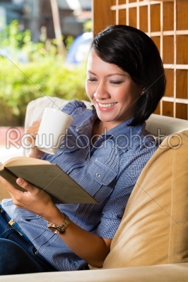 Asian girl with cup reading book