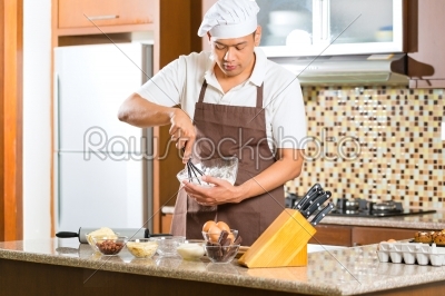 Asian man baking cake in home kitchen