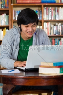 Asian man in library with laptop