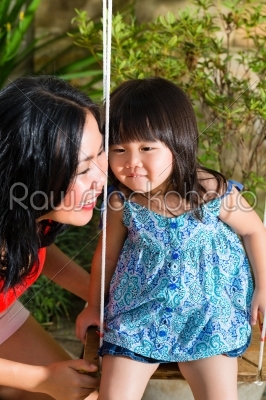 Asian Mother and daughter at home in garden