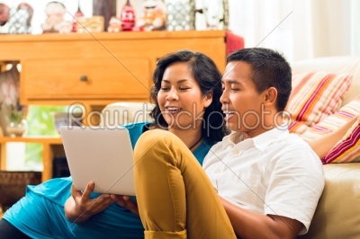 Asian people sitting in front of a notebook laughing 