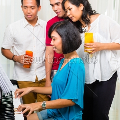Asian people sitting together at the piano