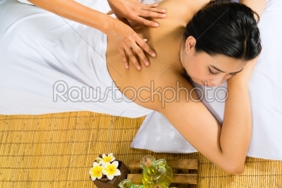 Asian woman having a massage in tropical setting