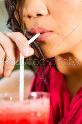 Asian woman in restaurant drinking