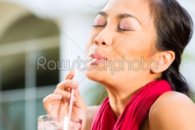 Asian woman in restaurant drinking