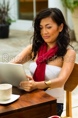 Asian woman is sitting in a bar or cafe outdoor