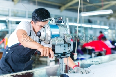 Asian worker using a machine in a factory