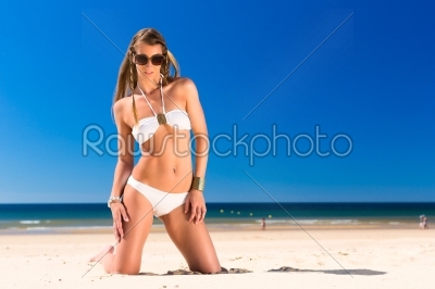 Attractive woman is kneeling  in the sun on beach