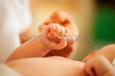 Baby gripping hand of mother