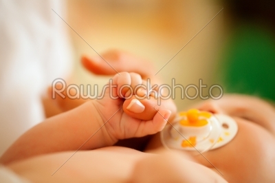 Baby gripping hand of mother
