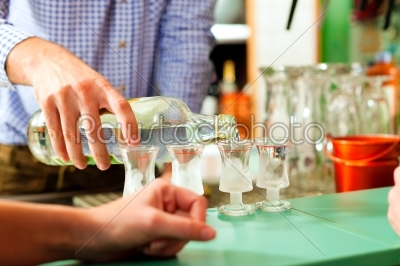 Barkeeper pouring hard liquor in glasses