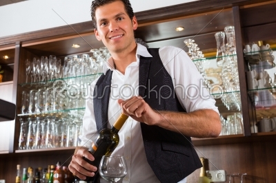 Barman standing behind bar with wine