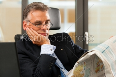 Boss in his office reading newspaper
