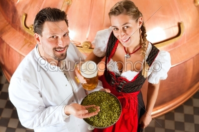 brewer and woman with beer glass in brewery