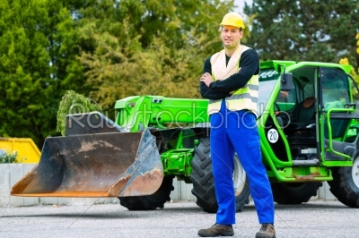 Builder in front of  construction machinery