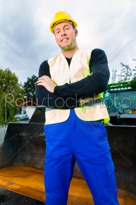 Builder on site in front of  construction machinery