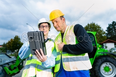 builders with blueprint on construction site