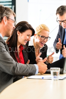 Business people looking at laptop with success