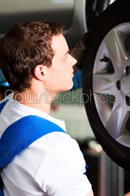Car mechanic in workshop changing tire