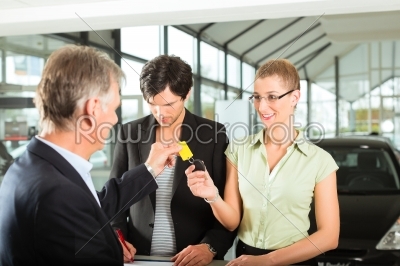 Car sales - dealer handing woman auto key