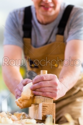 Carpenter with wood planer and workpiece in carpentry