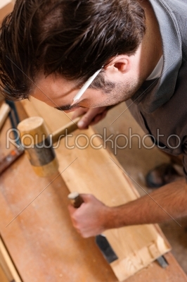 Carpenter working with a chisel and hammer in his workshop