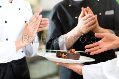 Chef team in restaurant kitchen with dessert