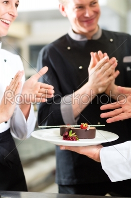 Chef team in restaurant kitchen with dessert
