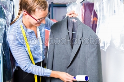 Cleaner in laundry shop checking clean clothes 