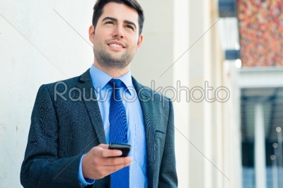 Confident businessman outdoor using phone