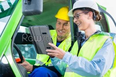 Construction worker discussing with engineer blueprints 