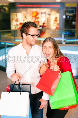 Couple - man and woman - in a shopping mall with colorful bags simply having fun