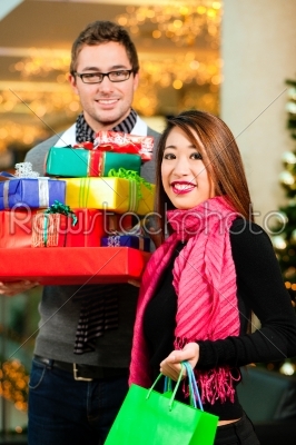 Couple Christmas shopping with presents in mall